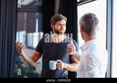 Kommen wir zu einem ernsthaften Gespräch. Zwei gutaussehende Geschäftsleute, die eine Diskussion im Büro haben. Stockfoto