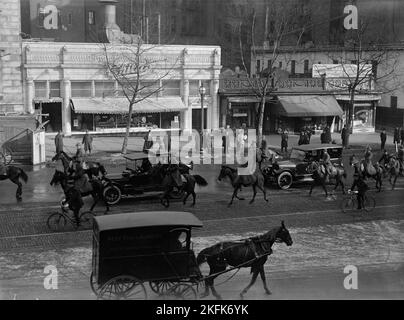 Childs Restaurant, Pennsylvania Avenue, Washington DC, 1917. Erster Weltkrieg: Zuschauer beobachten militärische Vorsteher, die die Kornege offizieller Autos begleiten. Der Heckwagen hat US- und deutsche Flaggen. Johann Heinrich von Bernstorff, deutscher Botschafter in den Vereinigten Staaten, verließ die USA am 3. Februar 1917, nachdem Präsident Woodrow Wilson die diplomatischen Beziehungen zu Deutschland abgebrochen hatte. Childs Restaurants war eine der ersten nationalen Speiseketten in den USA und Kanada. Auf der rechten Seite befinden sich Pressler Bros. Haberdaschers und die Büros von Gray Line Sightseeing Tours. Stockfoto