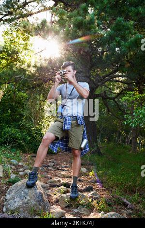 Teilen Sie die Schönheit der Natur. Ein hübscher Mann, der Bilder von der Landschaft um ihn herum fotografiert. Stockfoto