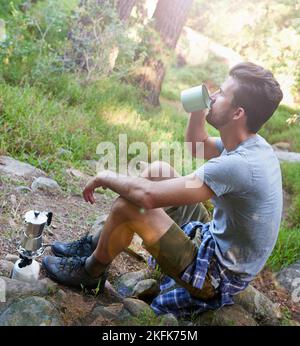 Alles, was man braucht, ist Kaffee und frische Luft. Ein junger Mann trinkt einen Kaffee, während er unterwegs ist. Stockfoto