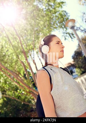 Musik motiviert sie. Eine sportliche junge Frau, die auf dem Weg ins Fitnessstudio Musik hört. Stockfoto