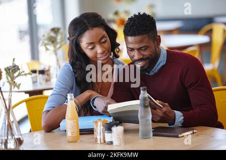 Ein junges Paar, das sich gegenseitig in Gesellschaft genießt, erklärt es ihr. Stockfoto