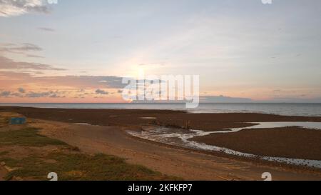 Ein Weitwinkel-Luftbild über dem Sandstrand mit pastellfarbener Sonnenuntergangswolkenlandschaft über dem Meer Stockfoto
