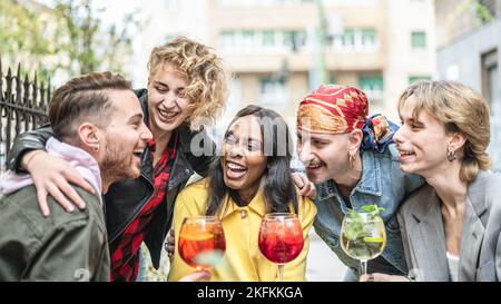 Eine Gruppe von Menschen aus verschiedenen Rassen, die an der Cocktailbar Getränke toasten, Freunde, die Spaß haben, Freunde mehrerer Generationen Stockfoto