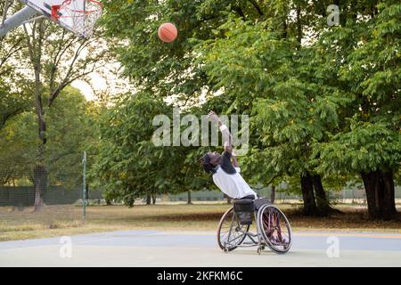 afroamerikanischer Basketballspieler in Aktion, Rollstuhlathlet gehen, um Punkt zu Korb, Inklusion und Vielfalt, Mann mit Behinderungen integr Stockfoto