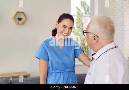 Freundliche Krankenschwester Betreuer lächelnde junge Frau unterstützt und hilft alten Mann in modernen Krankenhaus. Stockfoto