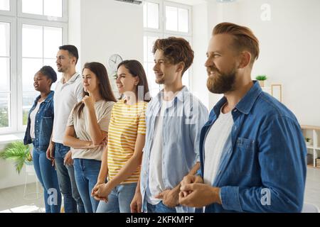 Verschiedene junge Menschen in legerer Kleidung hören während des persönlichen Entwicklungstrainings ihrem Coach zu. Stockfoto