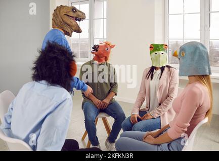 Patienten mit lustigen Tiermasken treffen sich bei einer Gruppentherapie-Sitzung und sprechen Stockfoto