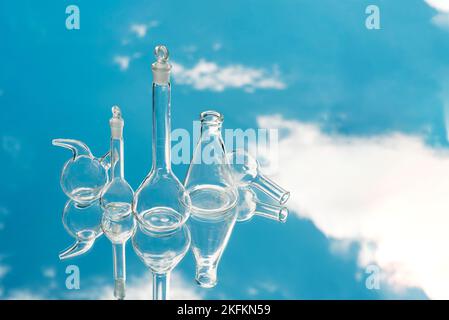 Verschiedene Laborglaswaren auf einem spiegelnden Hintergrund mit Himmelsreflexion. Konzept der modernen Biotechnologie Hintergrund, wissenschaftliche Laborforschung von Stockfoto
