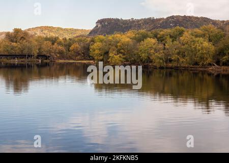 Die umliegenden Hügel und Bäume am Mississippi River in Winona, Minnesota, USA, sind von Kalksteinklippen und Herbstfarben umgeben. Stockfoto