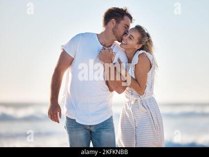 Glücklich, Liebe und Paar am Strand während eines Urlaubs für Romantik, Flitterwochen oder Entspannung. Glück, Kuss und junge Mann und Frau zu Fuß durch die Stockfoto