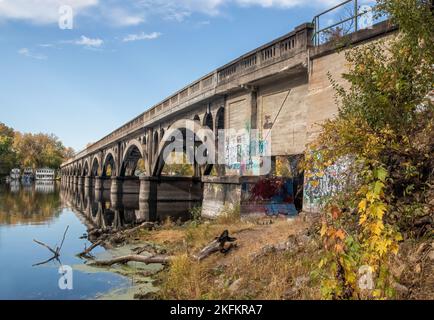 SeitenBlick auf die Latsch Island Bridge über das Backwaters des Mississippi River mit Hausbooten am gegenüberliegenden Ufer an einem Herbsttag in Winona, MN. Stockfoto