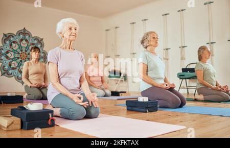Yoga, Lotus und eine Gruppe älterer Frauen im Fitnessstudio, die für spirituelle Gesundheit und Wellness meditieren. Meditation, Zen-Chakra und pensionierte Frauen trainieren Stockfoto