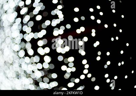 Silberfarbenes Bokeh leuchtet auf einem isolierten schwarzen Hintergrund. Abstrakter magischer Hintergrund mit Bokeh-Effekt, weißer Glitzer für Weihnachten. Overlay für Ihr Design.Hochwertige Foto Stockfoto