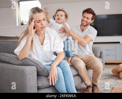 Familie, Stress und Kopfschmerzen der Mutter auf dem Sofa mit dem Vater, hyperaktive Energie und adhd-Kind. Müde, Burnout und Frau im Wohnzimmer mit Jungen und Stockfoto