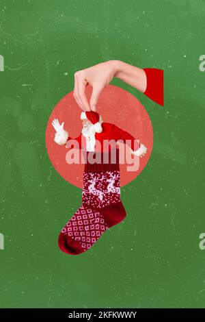 Vertikale kreative 3D Collage Foto-Postkarte von Arm halten lustige kleine weihnachtsmann in weihnachts-Socke isoliert auf grünem Hintergrund Stockfoto