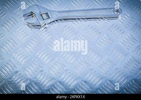 Verstellbarer Schraubenschlüssel auf geriffeltem Metallhintergrund Konstruktionskonzept. Stockfoto