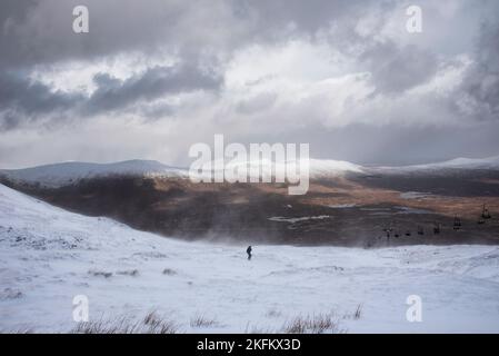 Wunderschöne Winterlandschaft von der Bergspitze in den schottischen Highlands hinunter in Richtung Rannoch Moor während Schneesturm und Spindrift von der Bergspitze hinein Stockfoto