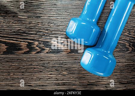 Blaue Kurzhanteln auf Vintage-Holzbrett. Stockfoto