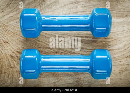 Blaue Hantelgewichte auf Holzbrett Sport Trainingskonzept. Stockfoto
