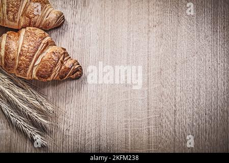 Zusammensetzung aus reifen Weizenrogen Ohren Croissants auf Holzbrett. Stockfoto