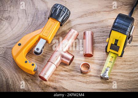 Kupfer Wasserrohr Cutter Steckverbinder Maßband auf Holzbrett Sanitär Brassware Konzept. Stockfoto
