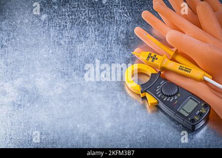 Digitale Strommesszange für elektrische Tester Isolationshandschuhe auf metallischem Hintergrund Stromkonzept. Stockfoto