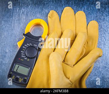 Sicherheitshandschuhe für Digitalamperemeter auf metallischem Hintergrund. Stockfoto