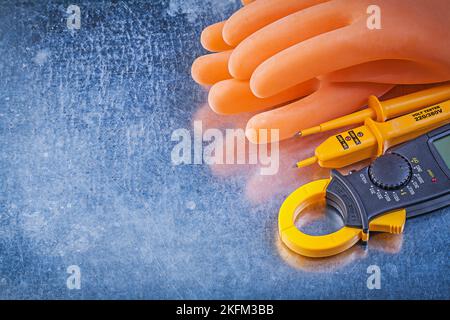 Digitale Strommesszange elektrische Tester isolierende Gummihandschuhe auf metallischem Hintergrund Strom Konzept. Stockfoto