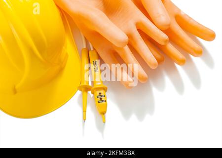 Dielektrische Handschuhe, elektrisches Prüfgerät und gelbes Helmaet, isoliert auf Weiß Stockfoto