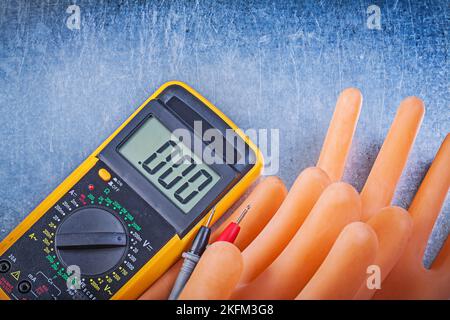 Digital-Multimeter isolierende Gummihandschuhe auf metallischem Hintergrund Stromkonzept. Stockfoto