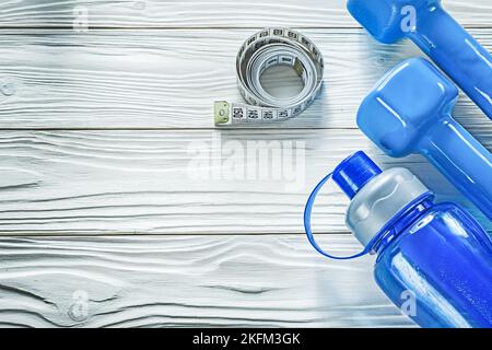 Kurzhanteln Maßband Wasserflasche auf Holzbrett Fitness-Konzept. Stockfoto