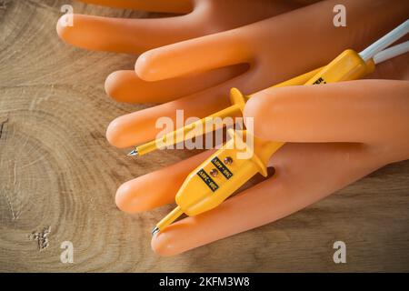 Elektrisches Prüfgerät Paar Isolierhandschuhe auf Holzbrett. Stockfoto