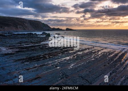 Wunderschöne Luftdrohnenlandschaft Sonnenuntergang Bild von Welcombe Mouth Beach in Devon England Stockfoto