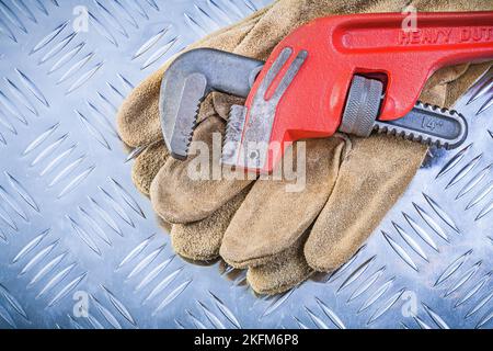 Leder-Schutzhandschuhe Affenschlüssel auf Wellblech Hintergrund Konstruktionskonzept. Stockfoto