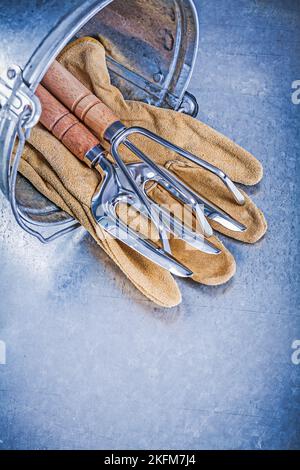 Metall Eimer Hand Rechen Kelle Gabel Leder Sicherheitshandschuhe auf metallischen Hintergrund Gartenkonzept. Stockfoto