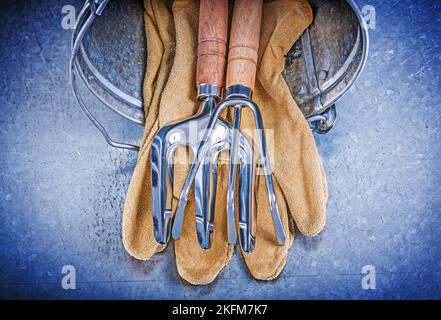 Metall Eimer Hand Rechen Kelle Gabel Leder Schutzhandschuhe auf metallischen Hintergrund Gartenkonzept. Stockfoto