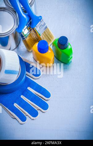 Farbdosen Flaschen Bürsten Kanalbänder und Schutzhandschuhe auf metallischem Hintergrund Baukonzept. Stockfoto