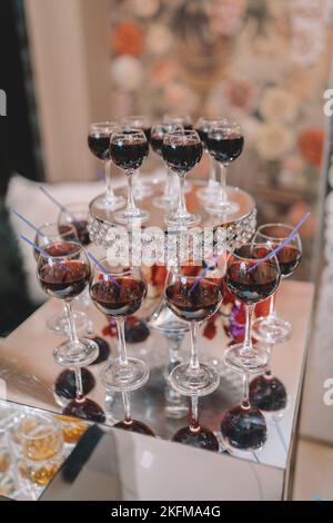 Glaspyramide mit Martini-Cocktail für einen festlichen Empfang bei der Hochzeit auf dem Tisch. Kosmopolitischer Kirschcocktail isoliert. Stockfoto