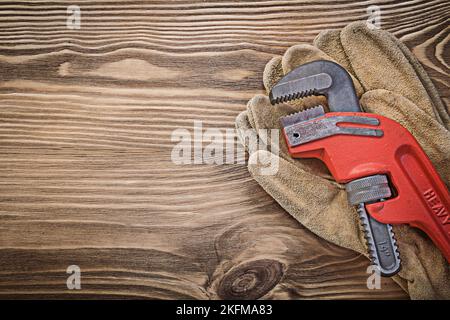 Ein Paar Schutzhandschuhe aus Leder mit Affenschlüssel auf Holzbrett Konstruktionskonzept. Stockfoto