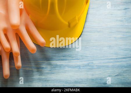 Paar Gummi-Isolierhandschuhe Gebäude Helm auf Holzbrett Elektrizitätskonzept. Stockfoto