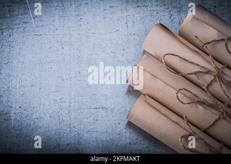 Stapel von alten Papierrollen auf zerkratztem metallischem Hintergrund. Stockfoto