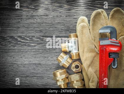 Rohrschraubenverschraubungen Sicherheitshandschuhe auf Holzbrett. Stockfoto