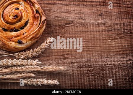 Reichhaltiges Rosinenbrötchen Haufen Weizenohren auf Eiche Holzbrett Essen und Trinken Konzept Stockfoto