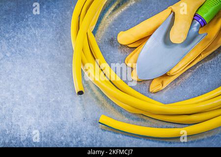 Gummi Gartenschlauch Schutzhandschuhe Handspaten auf metallischen Hintergrund Gartenkonzept. Stockfoto