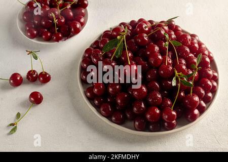 Reife Kirschen auf einem Teller auf hellem Hintergrund, leckere, süße Beerennaturprodukte ohne Pestizide Stockfoto