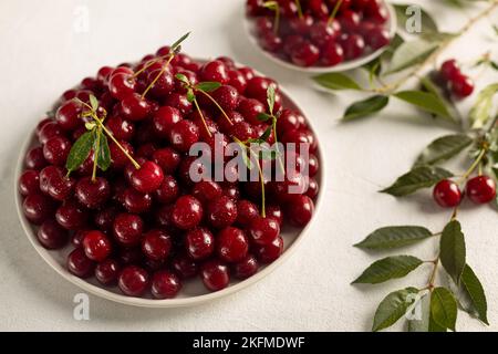 Reife Kirschen auf einem Teller auf hellem Hintergrund, leckere, süße Beerennaturprodukte ohne Pestizide Stockfoto