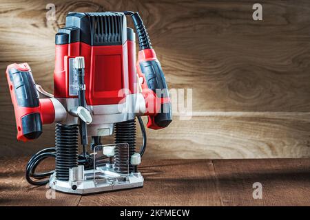 Seitenansicht rot Geschwindigkeit variable Leistung kleine Tauchfräse Fräsmaschine tragbare elektrische Hand Mini Holz Router auf Holzhintergrund Stockfoto