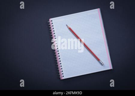 Weiß kariertes Copybook mit rotem Bleistift auf schwarzem Hintergrund Bildungskonzept Stockfoto