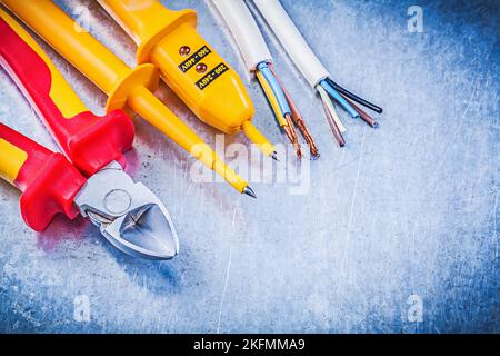 Gelbes elektrisches Prüfgerät Drähte Drahtschneider auf metallischem Hintergrund Elektrizitätskonzept. Stockfoto